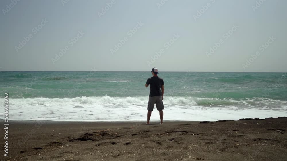 Wide shot of a standing man and looking at the stormy sea Wide shot of a standing man and looking at the stormy sea