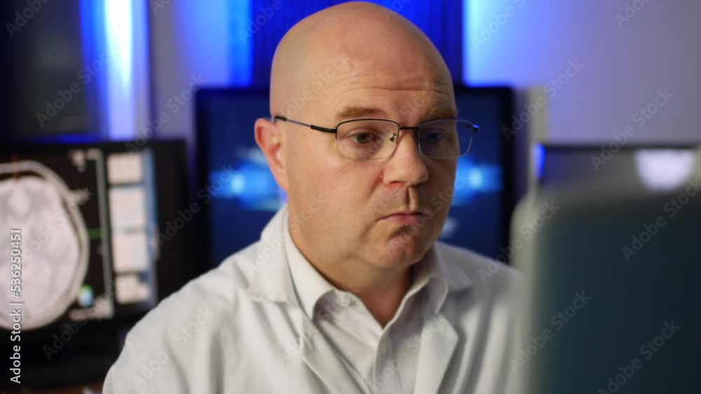 A doctor scientist working on a laptop in a research laboratory. The man is wearing glasses and working with xrays on a computer A doctor scientist working on a laptop in a research laboratory. The man is wearing glasses and working with xrays on a computer
