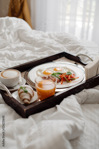 Tasty fresh breakfast with scrambled eggs and vegetables in bed at the hotel room