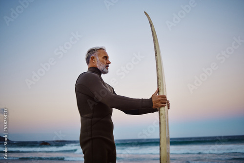 Wall Mural Surfer, surfboard and senior man at the beach during sunset after surfing on the waves in the sea water
