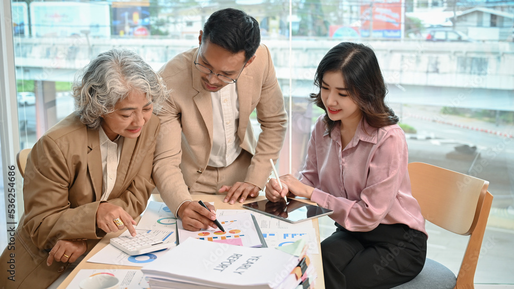 Group of professional Asian businesspeople analyzing financial yearly report together Group of professional Asian businesspeople analyzing financial yearly report together