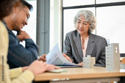 Aged Asian female executive manager in the meeting with her financial management team.