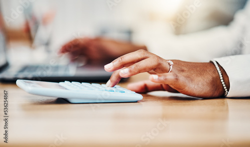 Accountant doing budget planning, money and finance management and bookkeeping or tax. Black woman using calculator, laptop and financial accounting at her desk in a corporate office closeup.