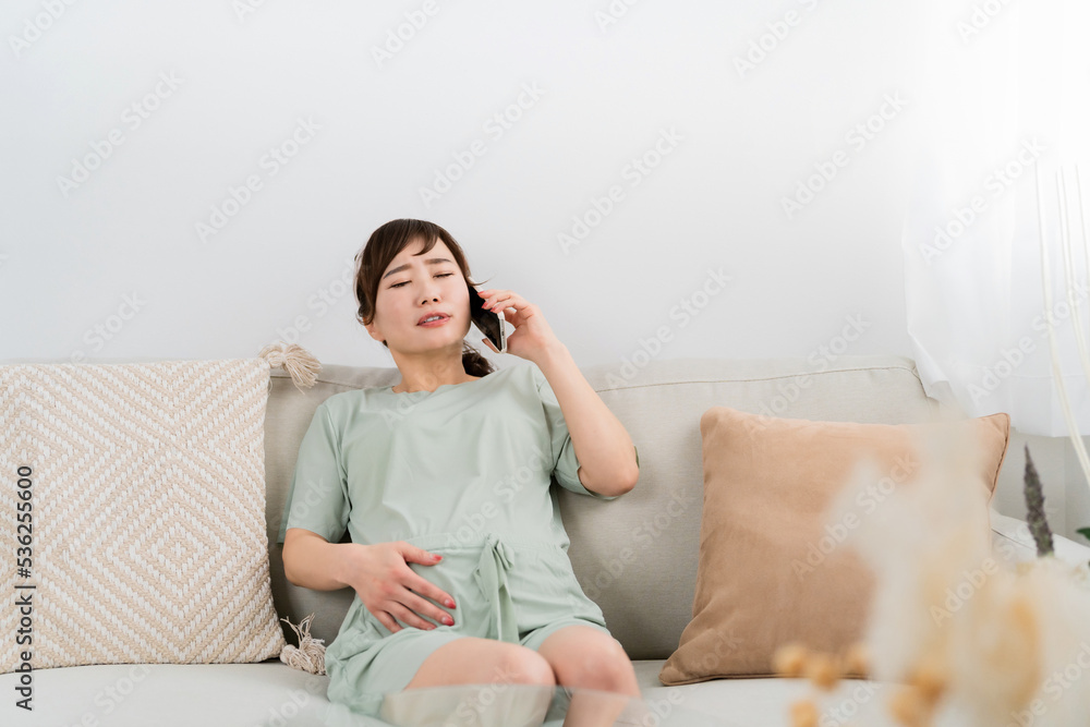 陣痛がきて電話するアジア人女性（腹痛・胃腸炎・食中毒）
