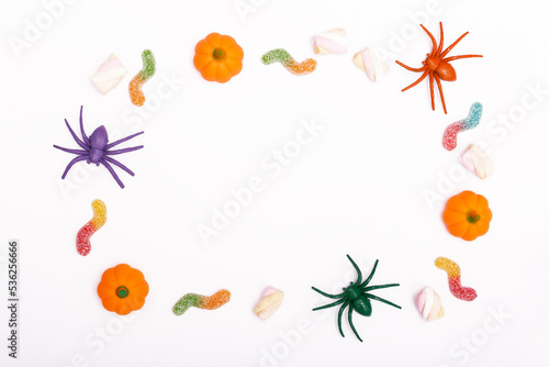Halloween concept. Frame from spiders  mini pumpkins  marshmallows and jelly worms on a white background. Traditional autumn holiday. flat lay  minimalism  from above