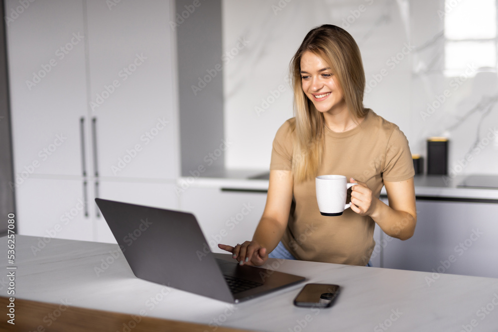 Woman drinking tea while on her laptop. Working from home in quarantine lockdown