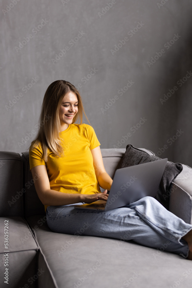 Young pretty woman using her laptop while relaxing on sofa Young pretty woman using her laptop while relaxing on sofa