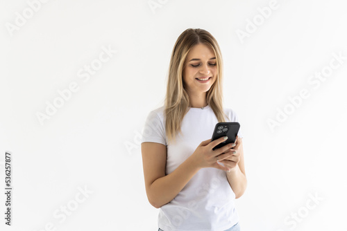 Photo of a shocked surprised young woman posing isolated over white wall background using mobile phone.