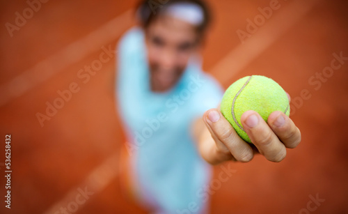 Young handsome tennis player with racket and ball prepares to serve at beginning of game or match. © NDABCREATIVITY
