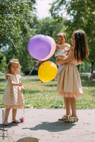 children playing with balloons in a park on summer day photo