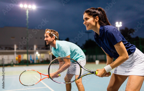 Tennis sport people concept. Mixed doubles player hitting tennis ball with partner standing near net © NDABCREATIVITY