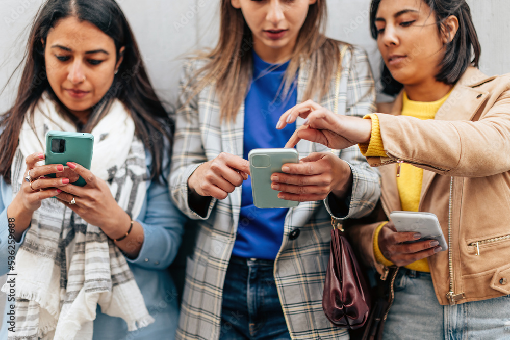 Fototapeta premium three multiethnic young ladies connected with cellphone