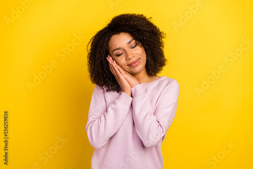 Photo of young pretty girl arms touch cheek asleep relax drowse dreamy isolated over yellow color background