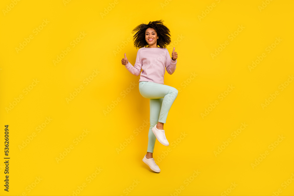 Full size photo of young pretty woman jump show thumb-up approve perfect isolated over yellow color background Full size photo of young pretty woman jump show thumb-up approve perfect isolated over yellow color background