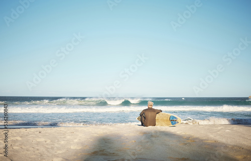 Surf, sea and sports with a man on the beach for surfing, fitness or training with a horizon view and sky mockup. Workout, exercise and health with a male surfer sitting on sand with his surfboard