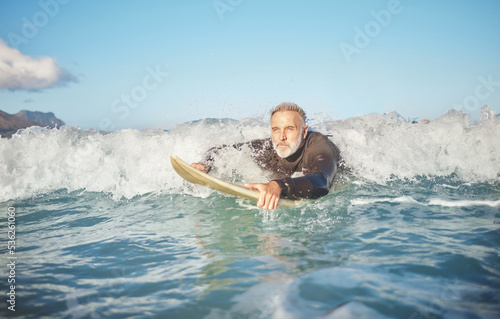 Ocean waves, senior man surfing on beach and healthy fitness lifestyle in Australia summer holiday. Elderly surfer swimming with surfboard, sea water exercise and relax in retirement travel vacation © S Fanti/peopleimages.com
