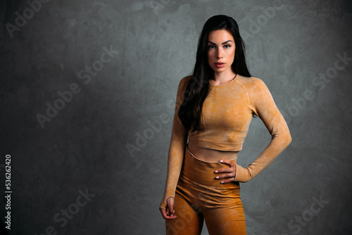 Beautiful fitness girl posing against grey wall background