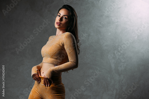 Beautiful fitness girl posing against grey wall background