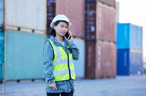 Logistics, phone call and woman talking about shipping container on a phone while working at port. Asian insdustrial employee speaking about distribution of cargo and stock on a mobile at a warehouse