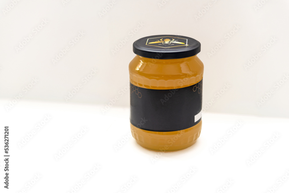 A jar of honey on a white background. Black label on the jar. Prepared for text or inscription.