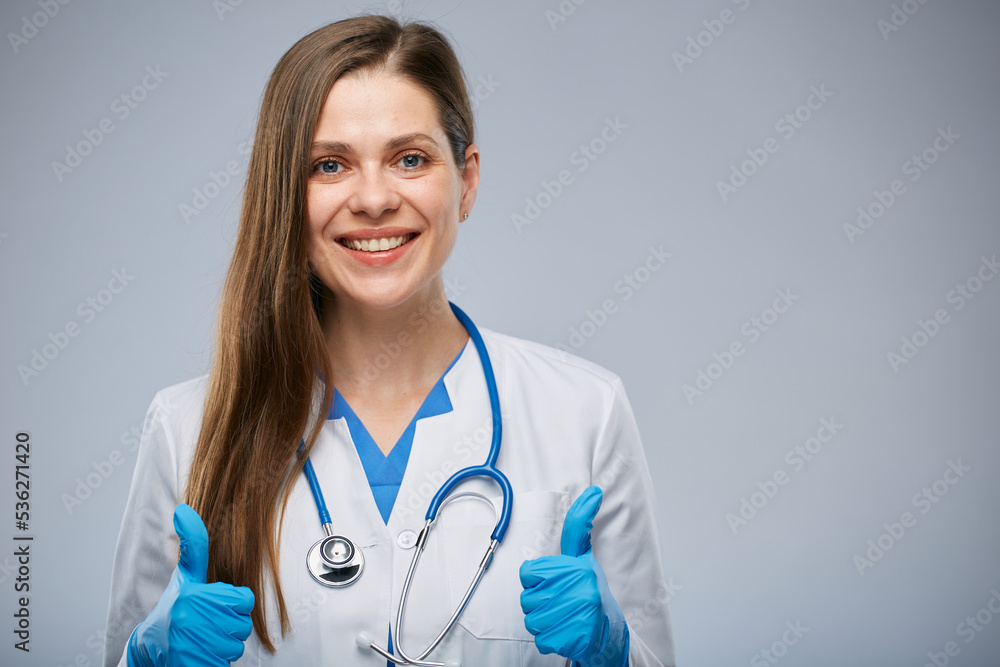 Smiling doctor woman in medical uniform showing thumbs up. Isolated portrait of female medical worker Smiling doctor woman in medical uniform showing thumbs up. Isolated portrait of female medical worker