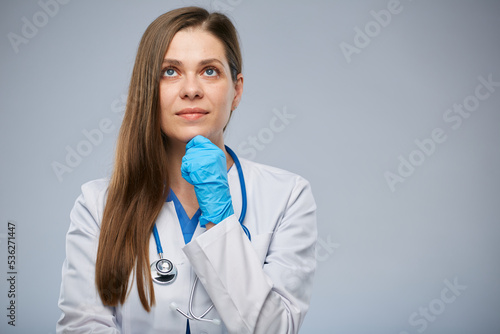 Thinking doctor woman in medical suit looking up. Isolated portrait of female medical worker