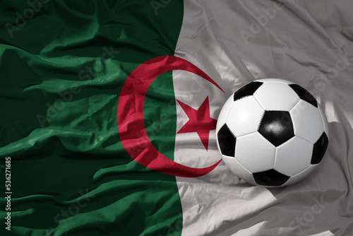 vintage football ball on the waveing national flag of algeria background. 3D illustration
