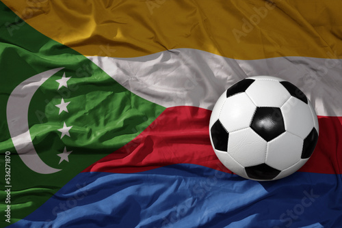 vintage football ball on the waveing national flag of comoros background. 3D illustration