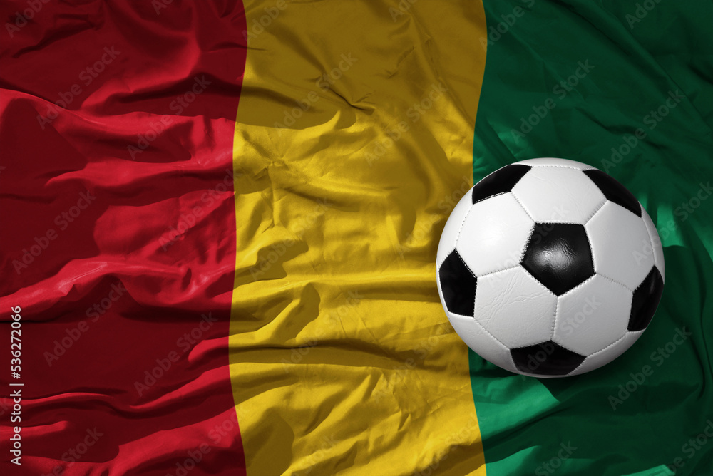 Naklejka premium vintage football ball on the waveing national flag of guinea background. 3D illustration
