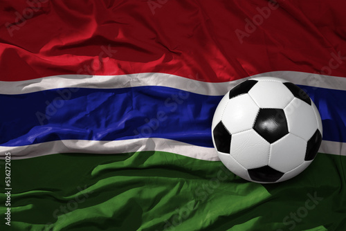vintage football ball on the waveing national flag of gambia background. 3D illustration