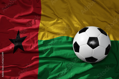 vintage football ball on the waveing national flag of guinea bissau background. 3D illustration