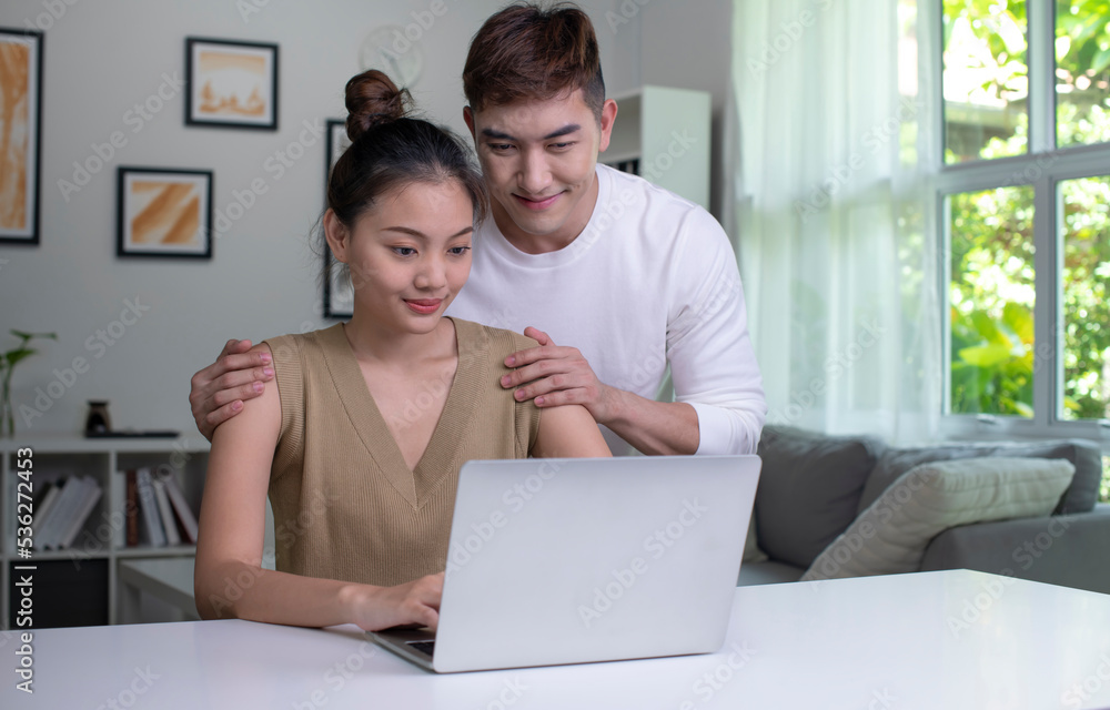 Happy young Asian couple communicating online on laptop. Loving Woman and Man embracing watching movie webinar on laptop. Happy young Asian couple communicating online on laptop. Loving Woman and Man embracing watching movie webinar on laptop.