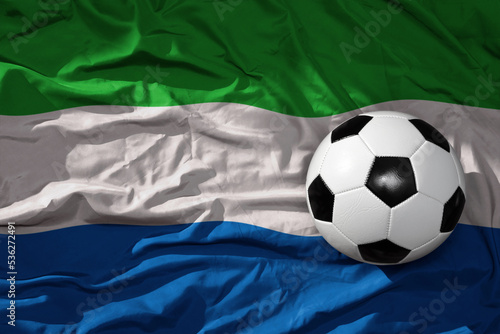 vintage football ball on the waveing national flag of sierra leone background. 3D illustration