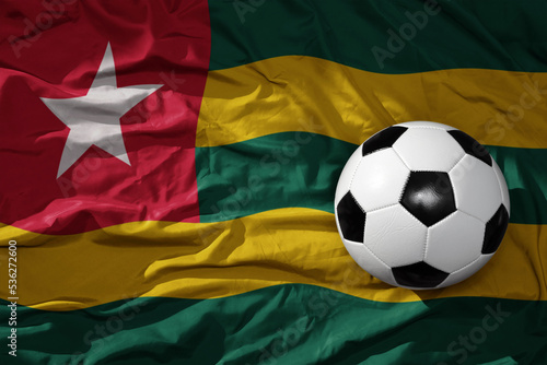 vintage football ball on the waveing national flag of togo background. 3D illustration