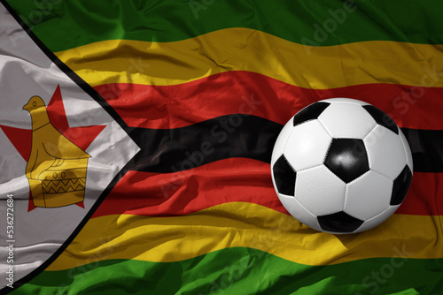 vintage football ball on the waveing national flag of zimbabwe background. 3D illustration