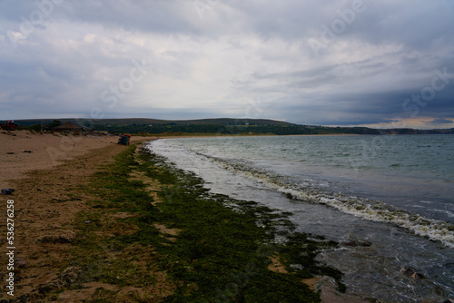 Grey skies over the beach in Oxwich Bay at low tide.