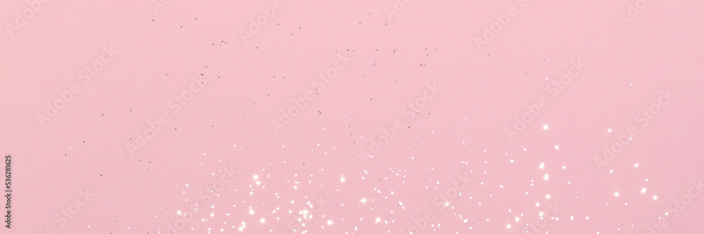 Sparkling silver glitter on pink background banner texture. Abstract holiday blurred lights header. Wide screen wallpaper. Panoramic web banner with copy space for design