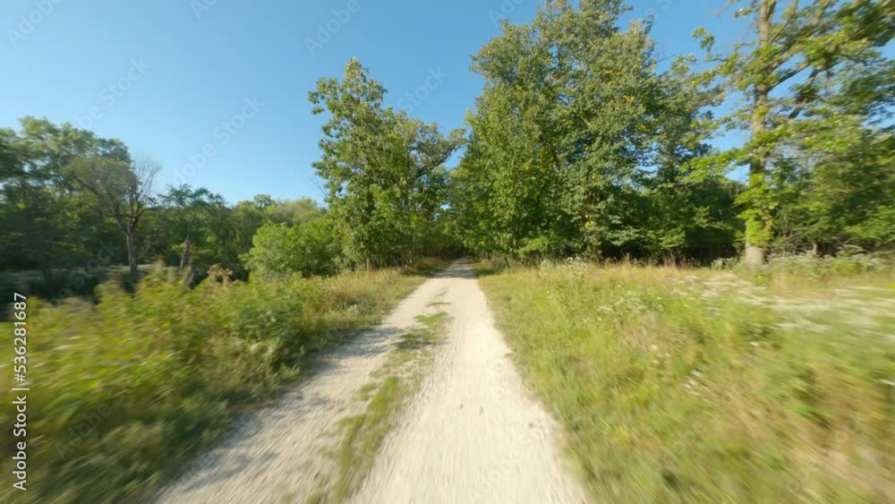Gravel and dirt biking and running trail path in the woods light and dark tree canopy. Smooth first person view POV cycling ride and running Gravel and dirt biking and running trail path in the woods light and dark tree canopy. Smooth first person view POV cycling ride and running