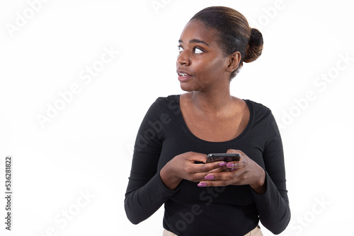 Portrait of serious African American woman using phone. Busy young model in black shirt with hair bun looking away with open mouth, dialing ads number. Advertising concept.