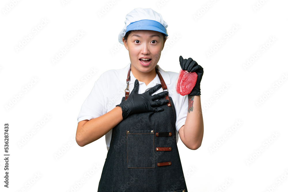 Young caucasian woman wearing an apron and serving fresh cut meat over isolated background surprised and shocked while looking right Young caucasian woman wearing an apron and serving fresh cut meat over isolated background surprised and shocked while looking right