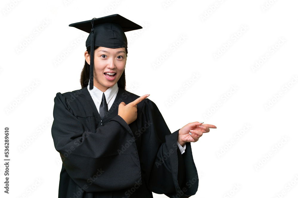 Young university graduate Asian woman over isolated background surprised and pointing side Young university graduate Asian woman over isolated background surprised and pointing side