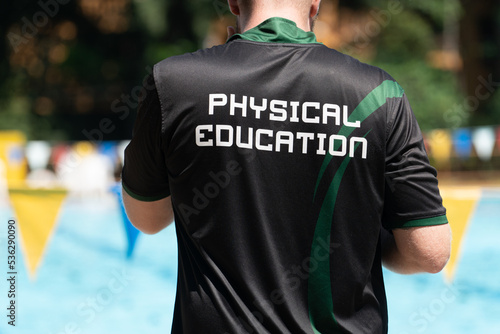 Back view of swimming coaches, wearing PHYSICAL EDUCATION shirt