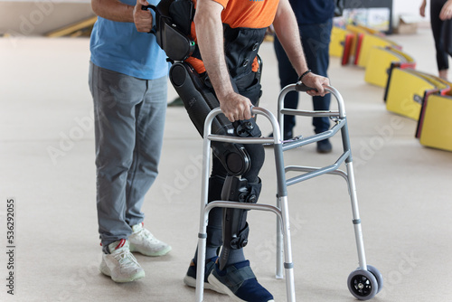 Obraz na plátne Boy with Mobility Problems in Lower Limbs in Upright Posture Walking Thanks to a