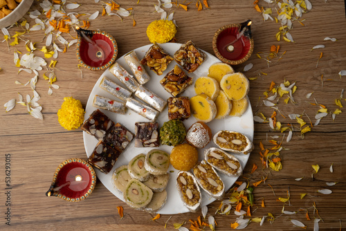 Mix indian sweets like kaju roll dryfruits barfi mango peda served in a plate photo