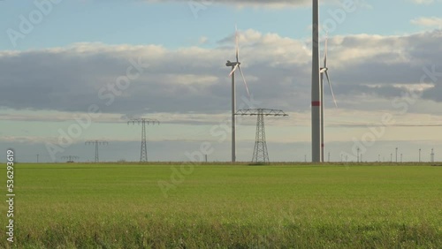 Wind turbine generates green energy in a field at sunset
