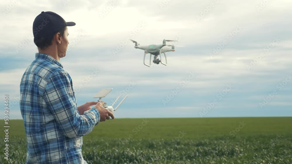 smart farming tech agriculture farming. man farmer engineer studies a wheat crop in a green field using a technology quadcopter. male red worker neck works in a green in a field lifestyle of corn smart farming tech agriculture farming. man farmer engineer studies a wheat crop in a green field using a technology quadcopter. male red worker neck works in a green in a field lifestyle of corn
