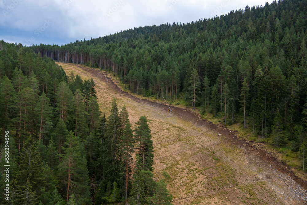 Aerial view of ski slope path in golden pine forest at Zlatibor mountain in Serbia, shot from cable car. Scenic view of Zlatibor mountain in summer.
Aerial view of ski slope path in golden pine forest at Zlatibor mountain in Serbia, shot from cable car. Scenic view of Zlatibor mountain in summer.