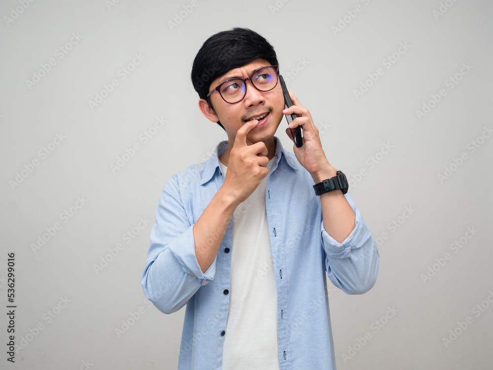 Young asian man using mobile phone gesture thinking and hesitate about something isolated Young asian man using mobile phone gesture thinking and hesitate about something isolated