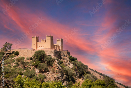 Imposing Kasbah of Beni Mellal which is a Berber castle and historical monument in the city of Beni Mellal, Morocco with a beautiful reddish and orange sky. This fortress is in the Tadla plain. photo