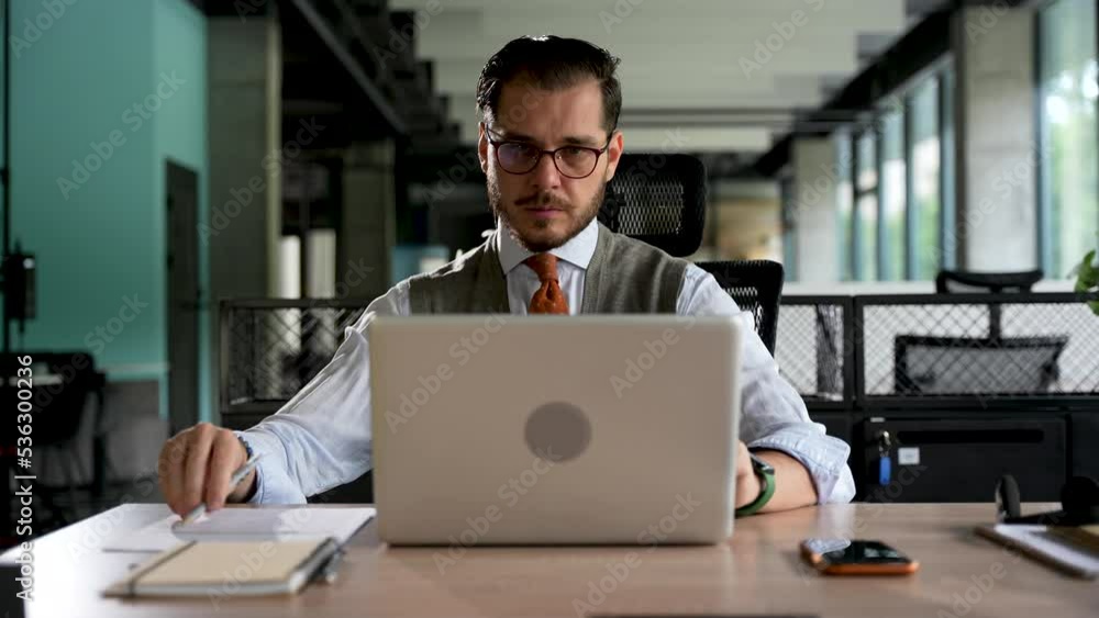 Businessman working on laptop computer at office. Male professional typing on laptop keyboard at workplace. Portrait of positive business man looking at laptop screen indoors Businessman working on laptop computer at office. Male professional typing on laptop keyboard at workplace. Portrait of positive business man looking at laptop screen indoors